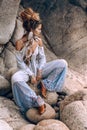 Cheerful young fashionable woman sitting on the stone beach