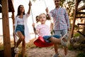 Cheerful young father and mother swing their cute little daughter on swing Royalty Free Stock Photo