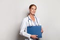 Cheerful young female doctor with stethoscope over neck looking at camera and smiling on white background Royalty Free Stock Photo