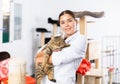 Female volunteer standing in animals shelter with gray tabby tomcat