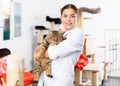 Female volunteer standing in animals shelter with gray tabby tomcat