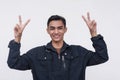 A cheerful young Filipino man making double peace signs. In a lighthearted and jovial mood. Isolated on a white background