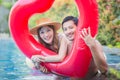 Cheerful young friends having fun in heart shaped inflatable, Happy young couple having fun at swimming pool. Happiness lifestyle Royalty Free Stock Photo