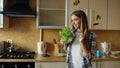 Cheerful young funny woman dancing and singing with lettuce microphone while cooking breakfast Royalty Free Stock Photo