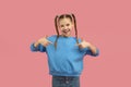 Smiling girl with braids pointing at herself