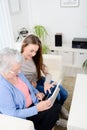 Cheerful young girl sharing time with an old senior woman and teaching internet with computer tablet Royalty Free Stock Photo