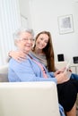 Cheerful young girl sharing time with an old senior woman and teaching internet with computer tablet Royalty Free Stock Photo