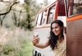 A young girl with smartphone by a car on a roadtrip through countryside, taking selfie. Royalty Free Stock Photo