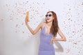 Cheerful young girl in summer clothes taking a selfie under confetti rain Royalty Free Stock Photo