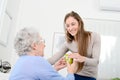 Cheerful young girl taking care of old senior woman at her home Royalty Free Stock Photo