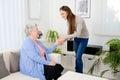 Cheerful young girl taking care of old senior woman at home Royalty Free Stock Photo