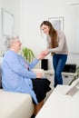 Cheerful young girl taking care of old senior woman at home Royalty Free Stock Photo