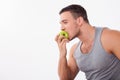 Cheerful young guy is biting a fruit greedily Royalty Free Stock Photo