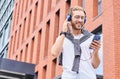 A cheerful young guy walks down the street and listens to music with headphones Royalty Free Stock Photo