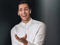 Cheerful young handsome man have a conversation with colleagues during meeting, posing over black wall, with wireless earphones. Royalty Free Stock Photo