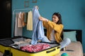 Cheerful young Hispanic woman packing suitcase, pack her clothes, getting ready for vacation at home. Millennial female Royalty Free Stock Photo