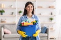 Cheerful young housewife holding bucket with cleaning supplies tools Royalty Free Stock Photo