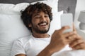 Cheerful young indian man chatting with girlfriend in bed Royalty Free Stock Photo