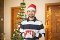 Cheerful Young Indian man holding gift box in hand celebrating christmas alone at home, new year, holiday, party, winter, december Royalty Free Stock Photo