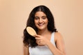 Cheerful young indian woman brushing her thick, wavy hair Royalty Free Stock Photo