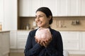 Cheerful young Indian woman holding toy ceramic pig with cash Royalty Free Stock Photo