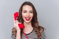 Cheerful young lady standing over grey wall talking by phone Royalty Free Stock Photo