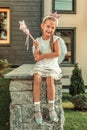 Cheerful young lady in white dress sitting on the railing