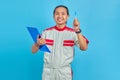 Cheerful young male mechanic holding clipboard and pointing with pen on blue background