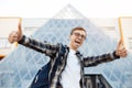 Cheerful young male student in casual outfit with bright smile holding show ok gesture while standing in front of triangle