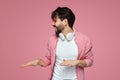 Cheerful young man with beard and pink sunglasses looking super amazed and excited at camera while dancing on pink background Royalty Free Stock Photo