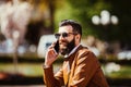Cheerful young man with beard talking on the mobile phone and smiling while near his bicycle. Royalty Free Stock Photo
