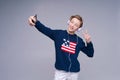 Cheerful young man in blue sweater posing on gray background, studio portrait.