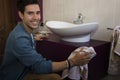 Cheerful young man cleaning the bathroom