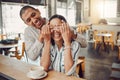 Cheerful young man covering his girlfriends eyes and surprising her while sitting in a cafe. Happy young mixed race Royalty Free Stock Photo