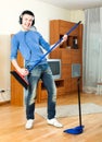 Cheerful young man with dustpan and brush