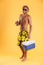 Cheerful young man in hat and sunglasses holding cooler bag Royalty Free Stock Photo