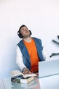 Cheerful young man in headphones listening to the music while sitting at his working place Royalty Free Stock Photo