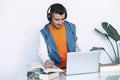 Cheerful young man in headphones listening to the music while sitting at his working place Royalty Free Stock Photo