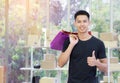 Cheerful young man holding colorful shopping bags, giving thumb up, and looking at the camera while standing in the office Royalty Free Stock Photo