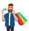 Cheerful young man holding shopping bags. Male character showing a credit, debit, ATM, bank card in hand. Modern lifestyle, Royalty Free Stock Photo