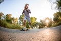 Cheerful young man holds little girl on his shoulders and ride skateboard in the park Royalty Free Stock Photo