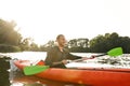 Cheerful young man kayaking on river, holding paddle, smiling away on a summer day Royalty Free Stock Photo