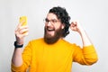 Cheerful young man is looking at his phone celebrating because he won Royalty Free Stock Photo