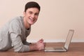 Cheerful young man lying on floor with laptop. Royalty Free Stock Photo