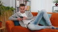 Cheerful young man lying on sofa, using mobile phone share messages on social media application Royalty Free Stock Photo