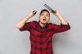 Cheerful young man in plaid sirt holding laptop over head Royalty Free Stock Photo