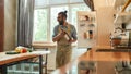 Cheerful young man, professional cook in apron taking a bottle of wine and vegetables out of the fridge while getting Royalty Free Stock Photo