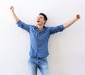 Cheerful young man with raised arms celebrating