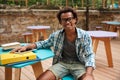 Cheerful young man sitting and smiling in outdoor cafe Royalty Free Stock Photo