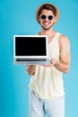 Cheerful young man standing and holding blank screen laptop Royalty Free Stock Photo